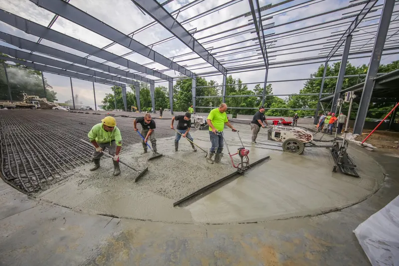 Crew screeding concrete over the rink floor piping