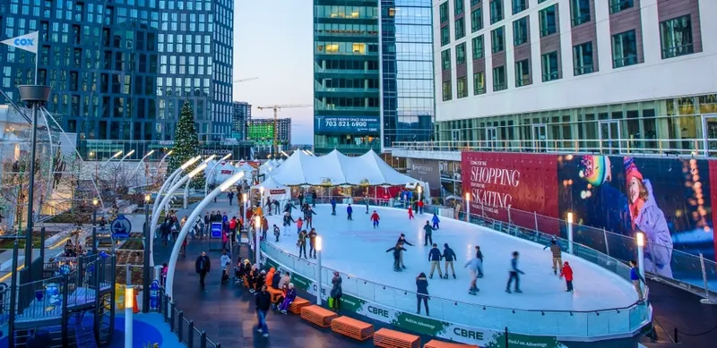 Outdoor plaza rink crowded with skaters between office buildings